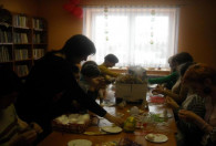 Zdjęcie przedstawia dzieci i dorosłych ozdabiających jajka wielkanocne metodą tzw. Quillingu.