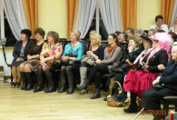 grupa kobiet siedząca na krzesłach pod sceną