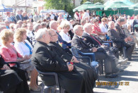 grupa ludzi siedząca na krzesłach pod sceną na dożynkach