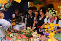 grupa kobiet stojąca przy stołach z jedzeniem na święcie plonów