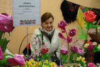 Zdjęcie przedstawia Panią Janinę Kwiatkowską z kwiatkami na wystawie