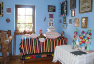 Zdjęcie przedstawia pokój z ozdobionymi ramami obrazów na ścianie oraz wycięte z bibuły kwiaty w wazonie na stole